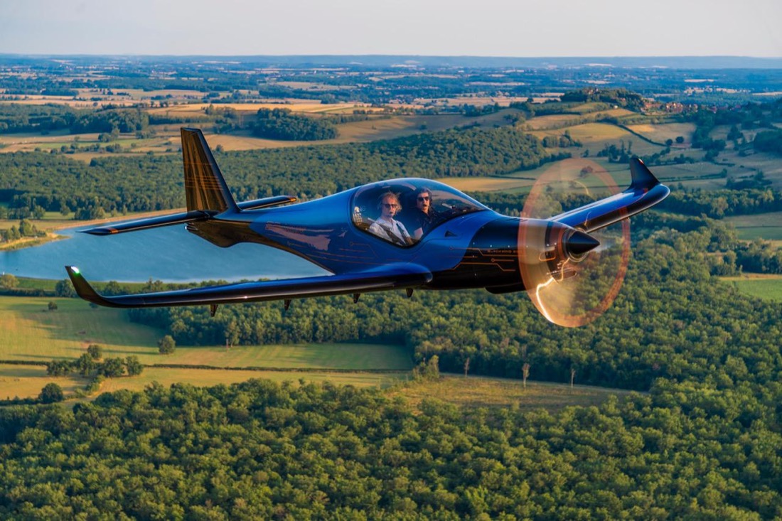 Blackwing 650 RG bleu en vol au-dessus de la campagne, deux occupants à bord