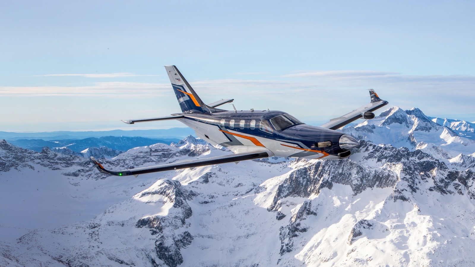 Daher TBM 980 bleu marine en vol au-dessus de montagnes enneigées, vue latérale