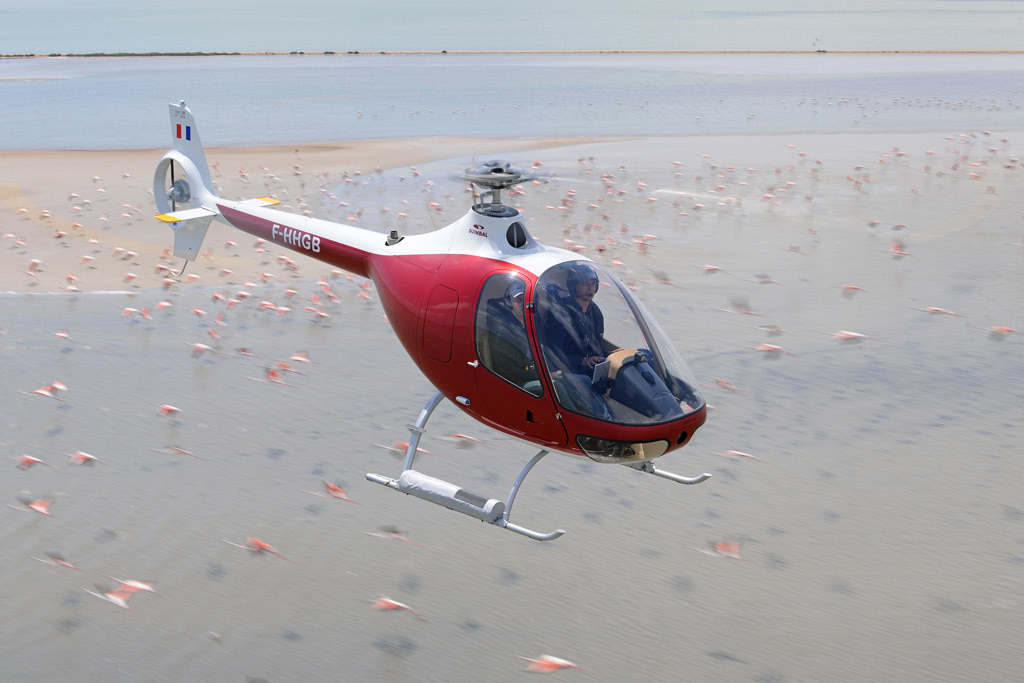 Guimbal Cabri G2 en vol au-dessus d'un plan d'eau, vue trois-quarts