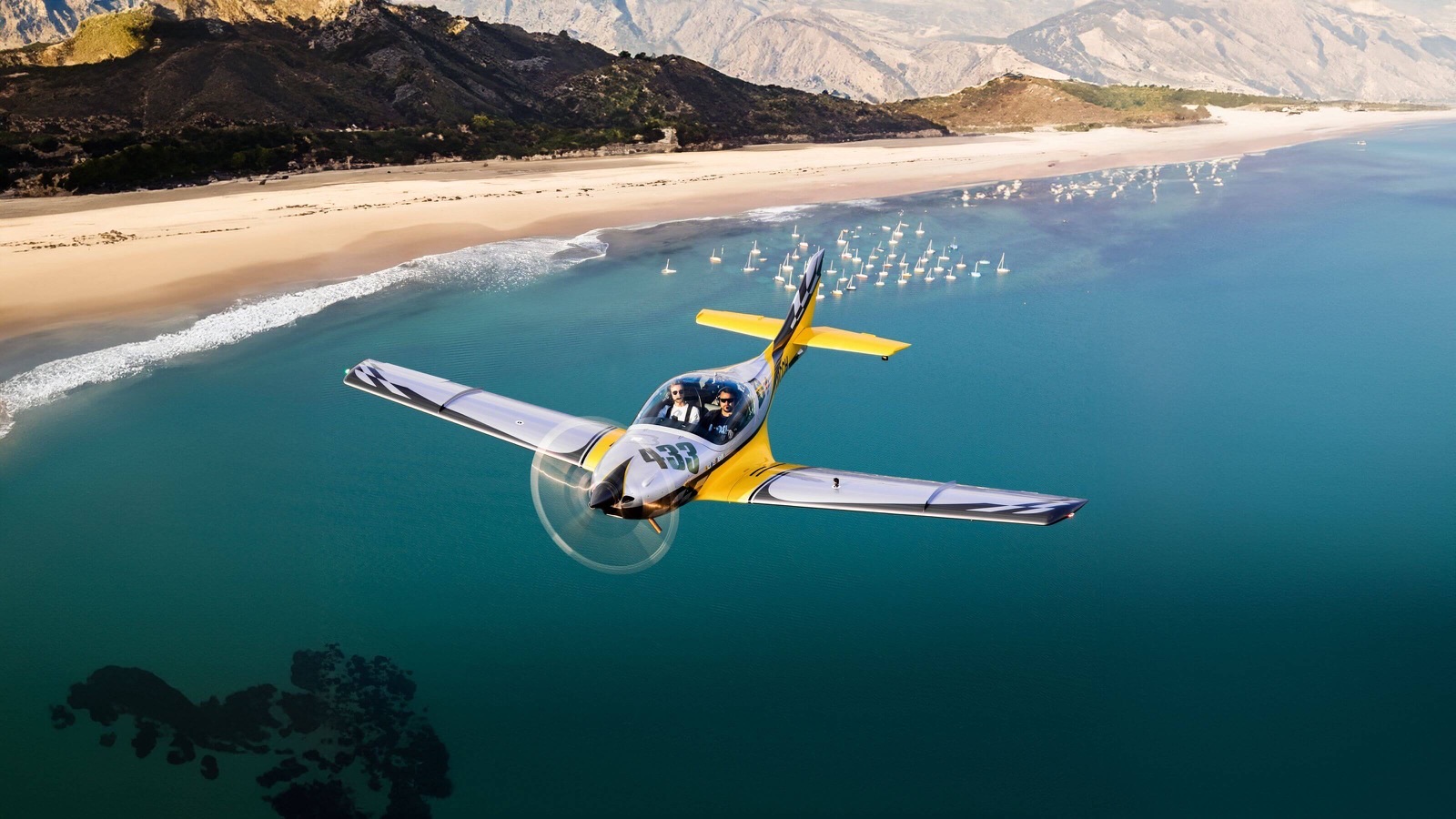 JMB Aviation VL3 en vol au-dessus d'une côte, livrée argent et jaune