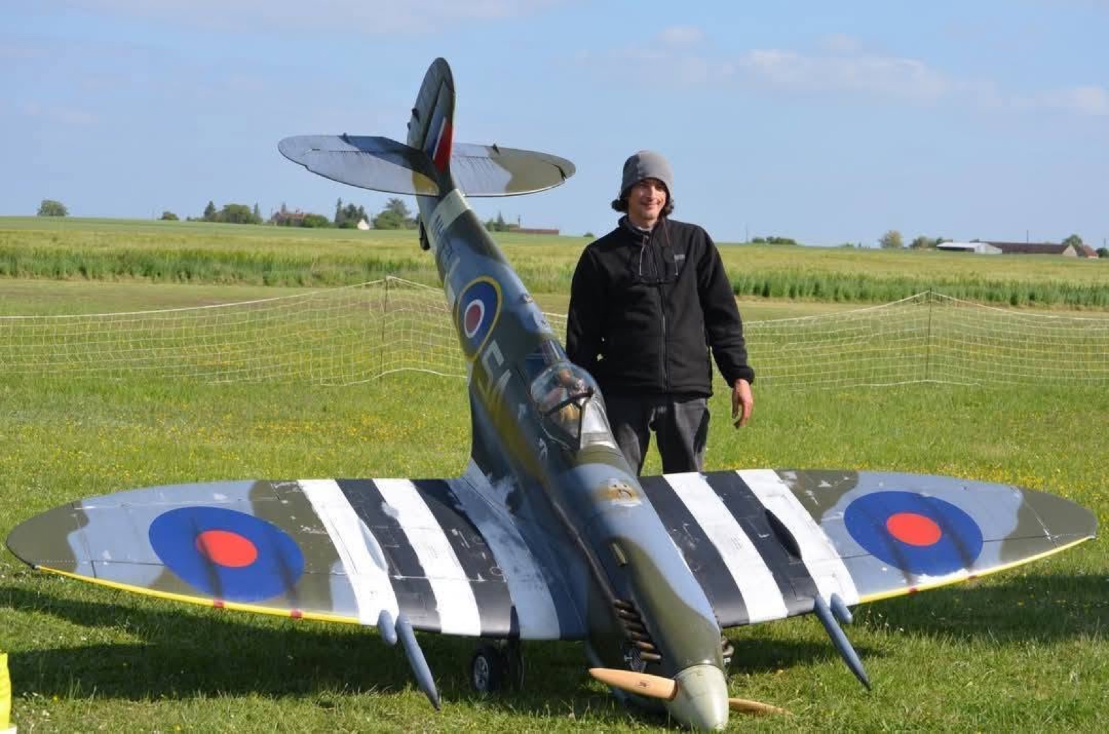Maquette de Supermarine Spitfire MK9 à l'échelle 1/3 posée dans l'herbe, un homme debout derrière l'aile donne l'échelle : la maquette lui arrive à la taille