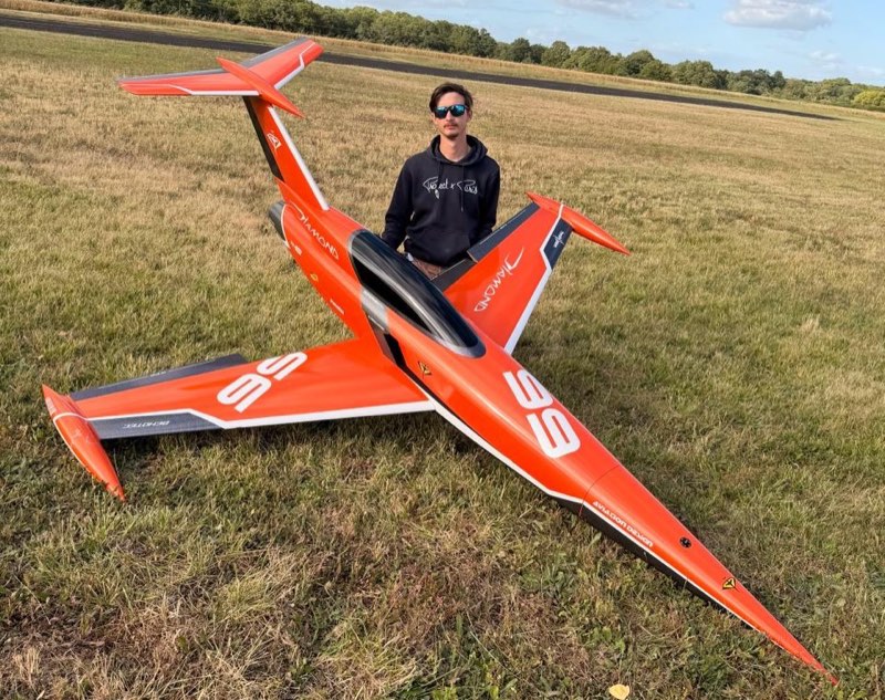 Diamond, jet d'aéromodélisme de vitesse orange numéro 56, Adrien Masson debout derrière le modèle sur un terrain de vol