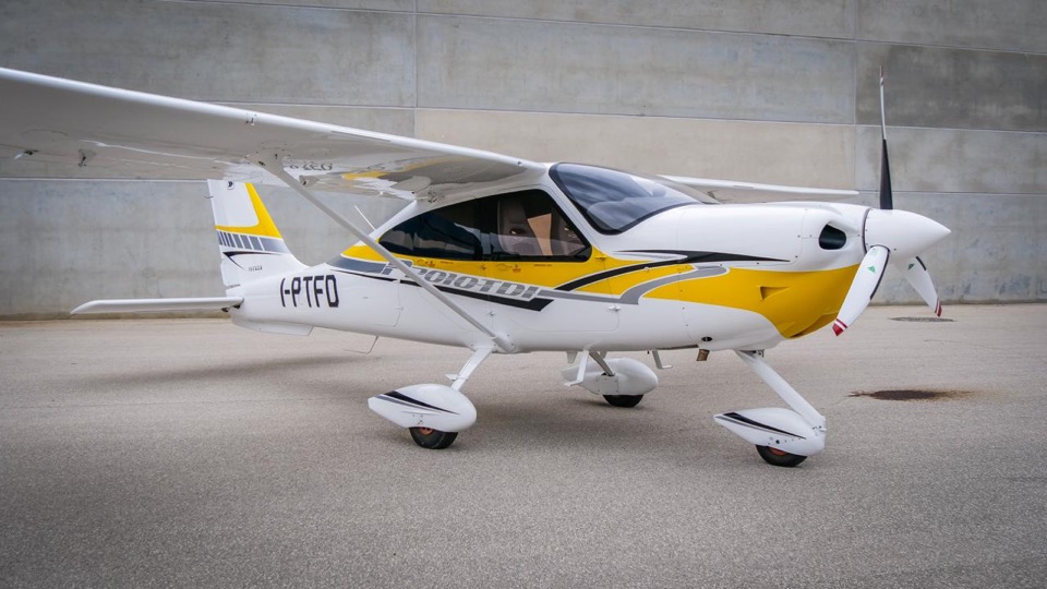 Tecnam P2010 TDI jaune et blanc au sol devant un hangar